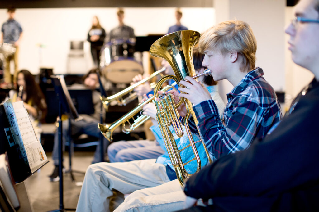 Photo of a boy playing a brass instrument in a band class
